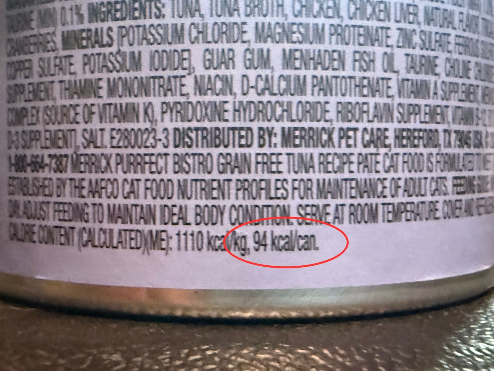 Close-up of a wet cat food can label with the calorie content, 94 kcal per can, circled in red